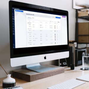 A desktop computer on a tidy office desk displays the 30 Day Free Trial appointments management dashboard, showing a list of scheduled entries and date details.